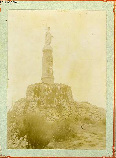 Une photographie originale ancienne en noir et blanc, d'un groupe de 13 hommes au pied d'une statue de Sainte.