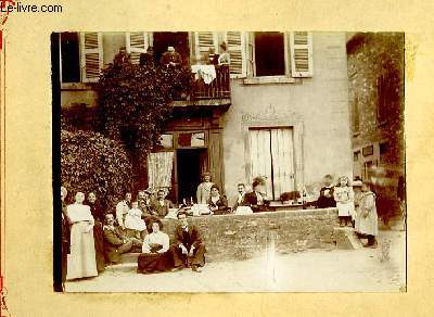Une photographie originale ancienne en noir et blanc, d'un groupe de villageois dans une ruelle et au balcon, se dsaltrant autour de quelques bouteilles de vins.
