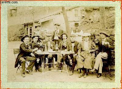 Une photographie originale ancienne en noir et blanc, d'un groupe 10 villageois regroups autour d'une table de jardin, se restaurant, buvant et fumant la pipe.